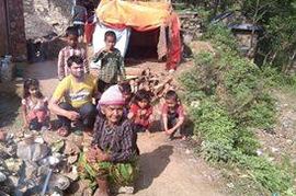 A family with young children and an elderly woman beside a tarpaulin shelter, cooking pots on the ground