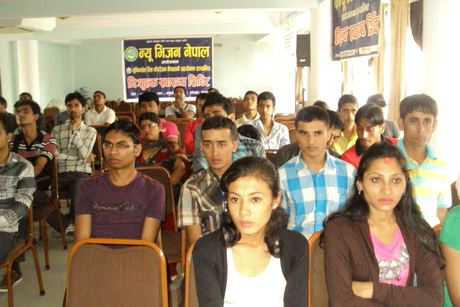 Young participants seated in rows in a hall beneath the New Vision Nepal banner