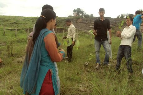 A volunteer planting a sapling in the open field at Mulpani